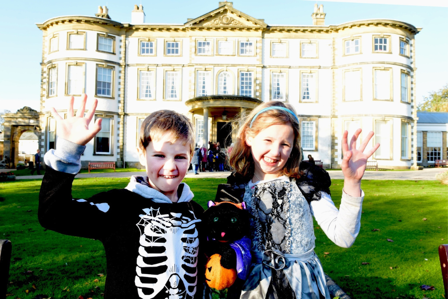 two children in halloween costumes outside sewer by hall